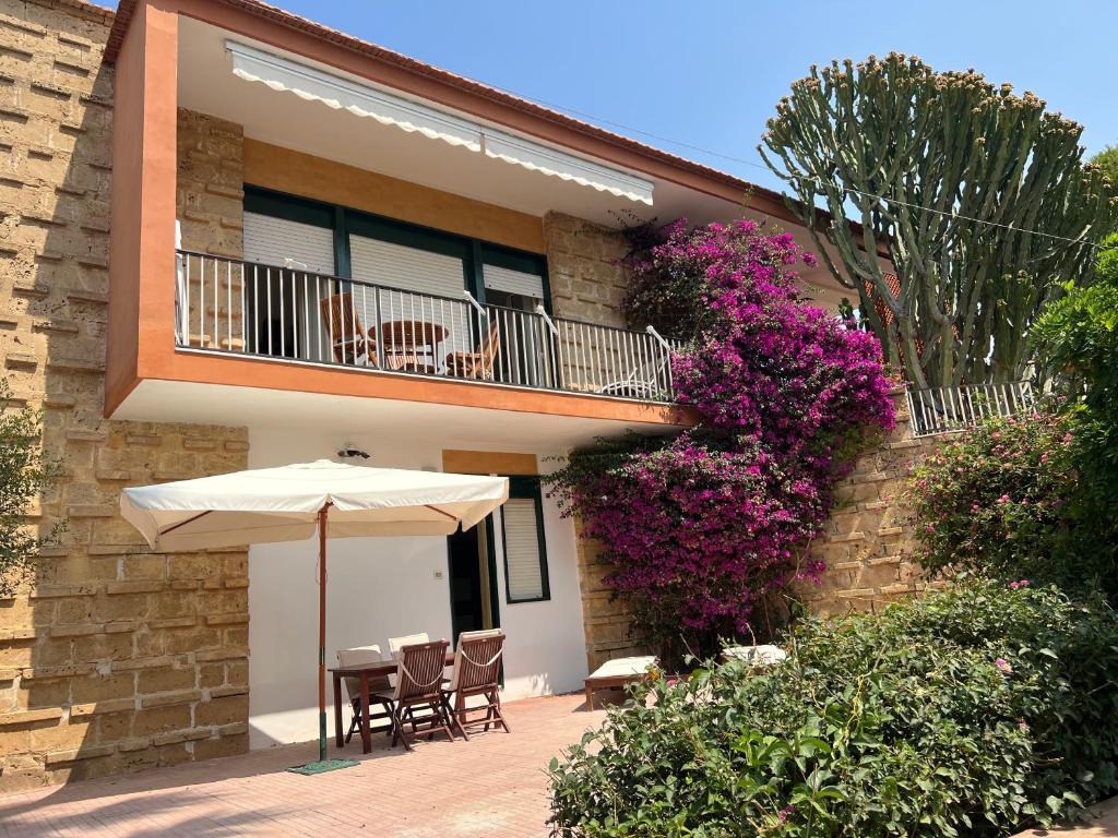 诺托玛丽娜Appartamentino in villa sul mare的一个带遮阳伞和椅子的庭院和一个阳台