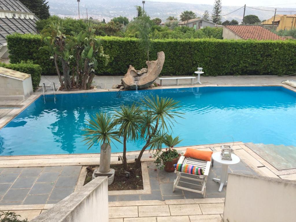 维多利亚Sicilia Bedda B&B的一个带桌子和棕榈树的大型蓝色游泳池