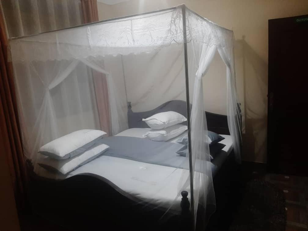 NjaraStarnford Hotel的卧室配有带白色床单和枕头的天蓬床。