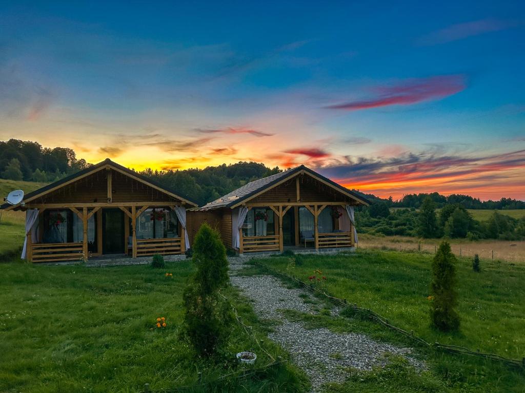 Satu ŞugatagCăsuțele din Poiană的两座位于田野的木制小屋,享有日落美景