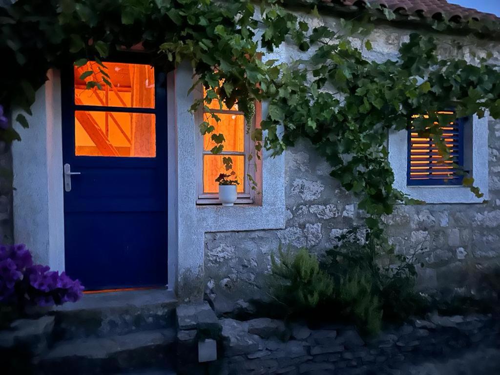 马斯林尼察Villa rustica bougainvillea的一座带蓝色门和两扇窗户的房子