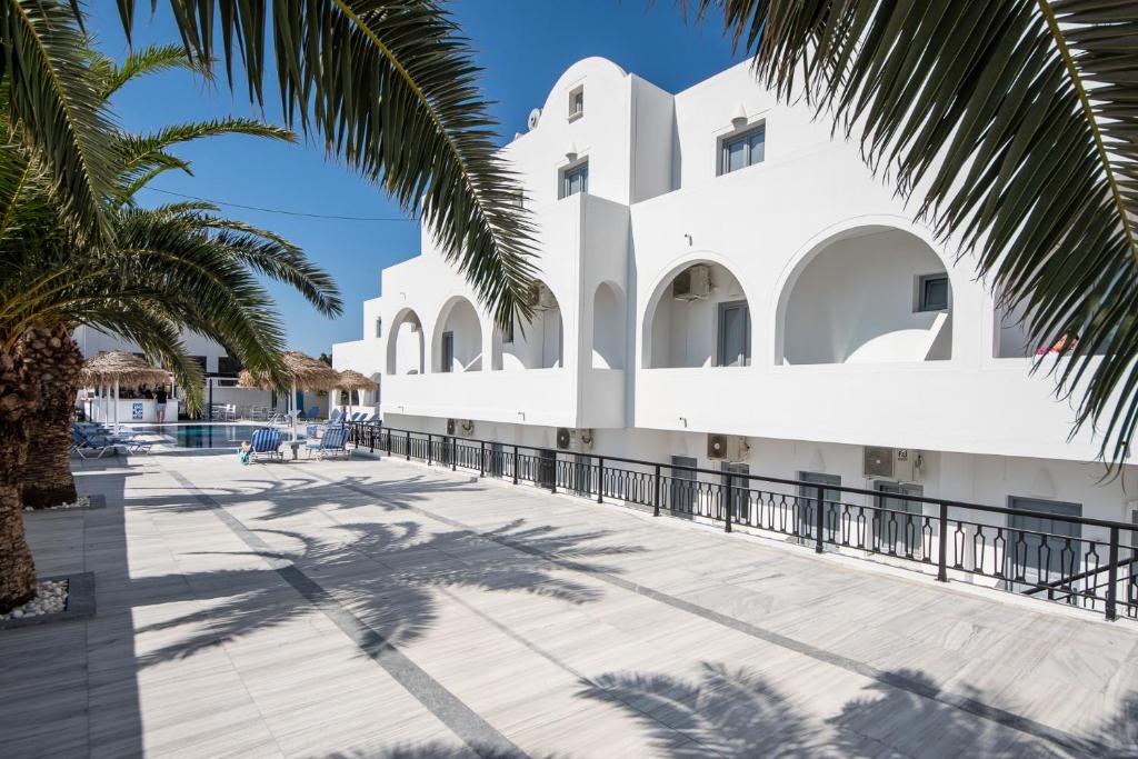 佩里萨瓦尔维斯别墅酒店的一座白色的建筑,前面有棕榈树