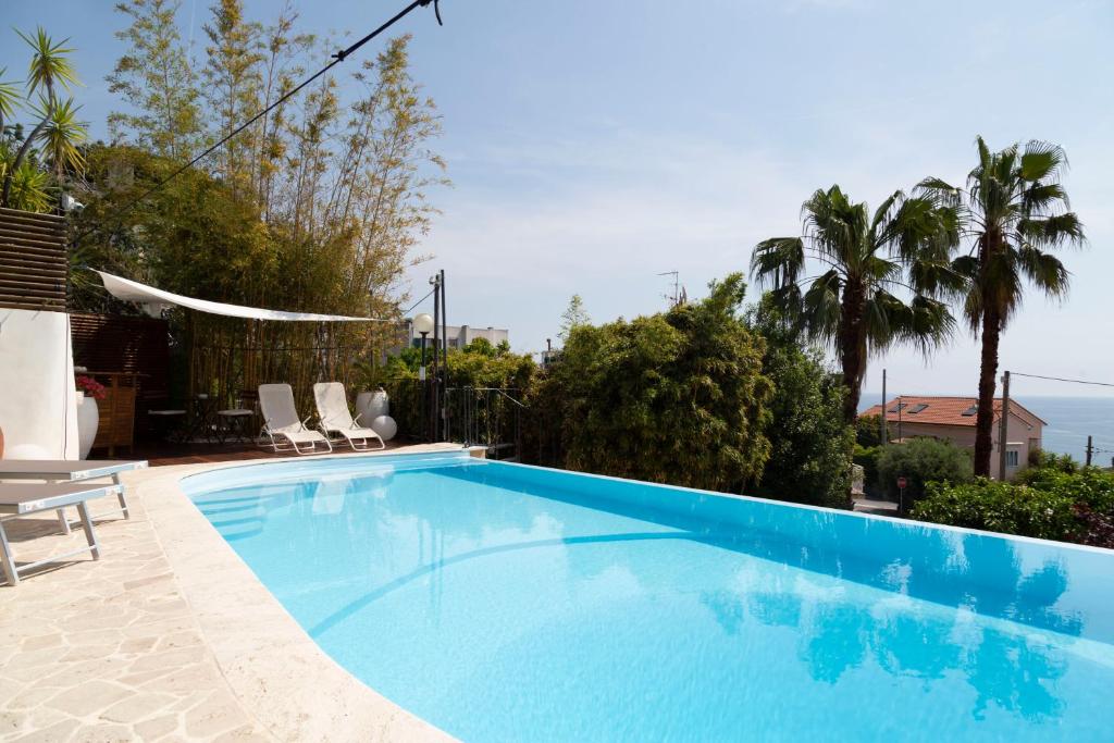 阿尔比索拉马里纳Casa Milena elegante dimora con piscina privata的一个带椅子和棕榈树的大型蓝色游泳池