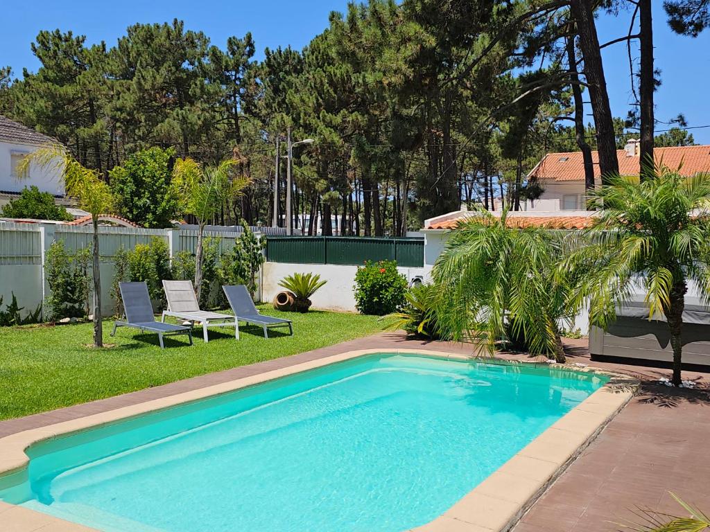 阿尔马达Guest House Ruceel Aroeira的庭院内的游泳池,配有两把草坪椅