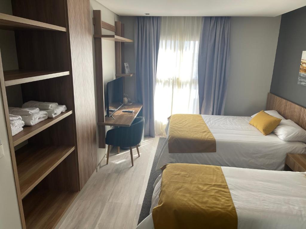 OlivaUrban Suites Oliva的酒店客房配有两张床和一张书桌