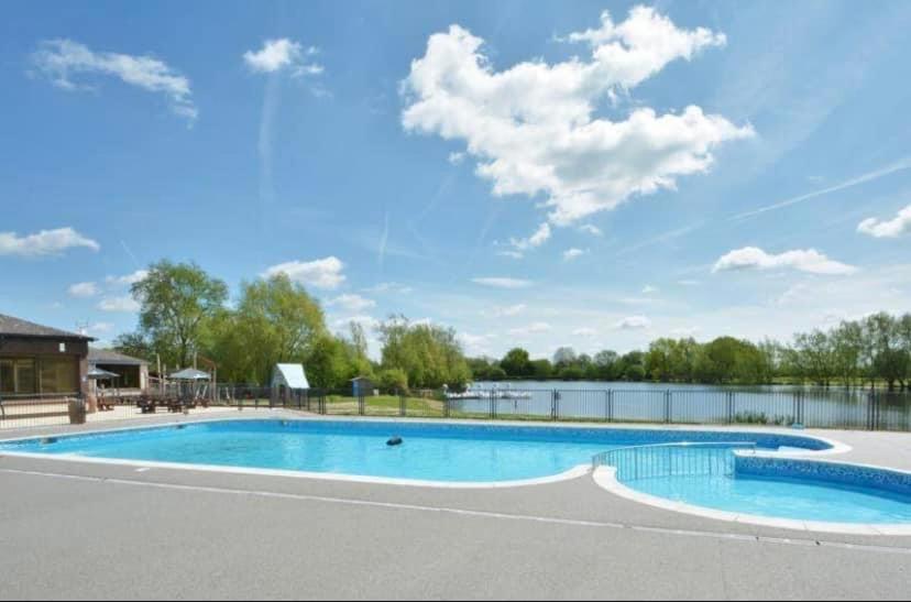 南塞尔尼Summer Breeze-Hoburne Cotswolds的一座带湖泊的游泳池