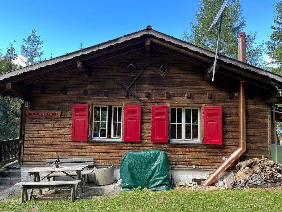 Beautiful Swiss chalet with breathtaking views and a sauna的小木屋配有红色百叶窗和野餐桌