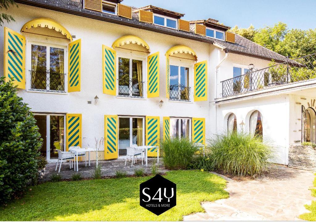 沃尔特湖畔韦尔登Boutiquehotel Caravella Velden by S4Y的上面有黄色和蓝色百叶窗的房子