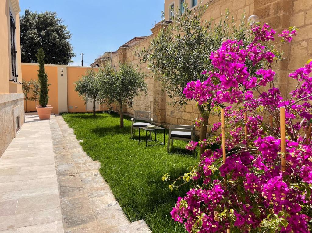 塔兰托Palazzo Pitagora的一座花园,花园旁边是一座建筑,鲜花盛开