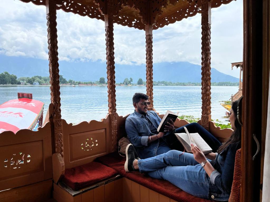 斯利那加New kolohai group of houseboats的坐在船上看书的男人和女人