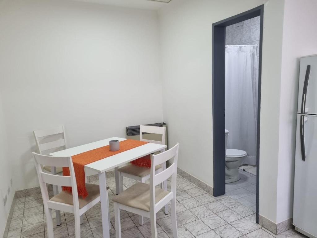 里奥加耶戈斯Hermoso departamento con patio en Rio Gallegos的厨房配有白色的桌椅和冰箱。