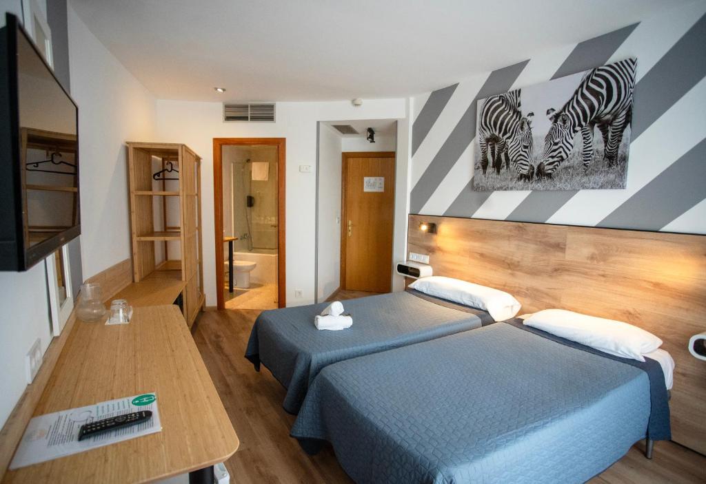 罗列特海岸Hotel Ridomar 365的卧室配有两张床,墙上有两颗斑马