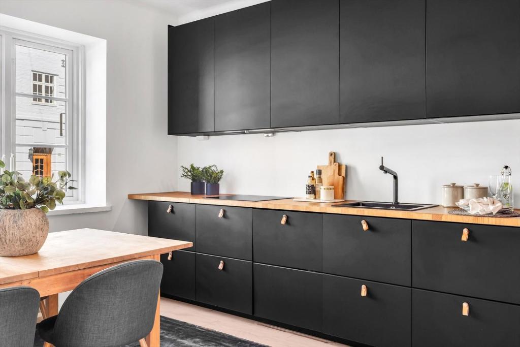 奥斯陆Apartment in the best part of Oslo的厨房配有黑色橱柜和木桌