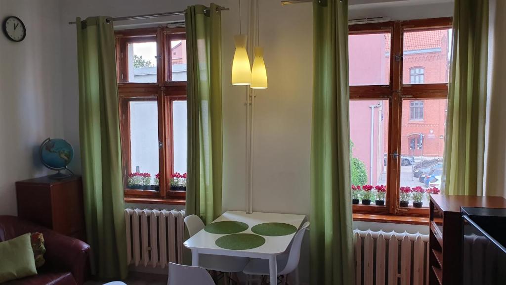 奥尔什丁Apartament Olsztyn Centrum的一间设有绿色窗帘的房间,窗户前设有一张桌子