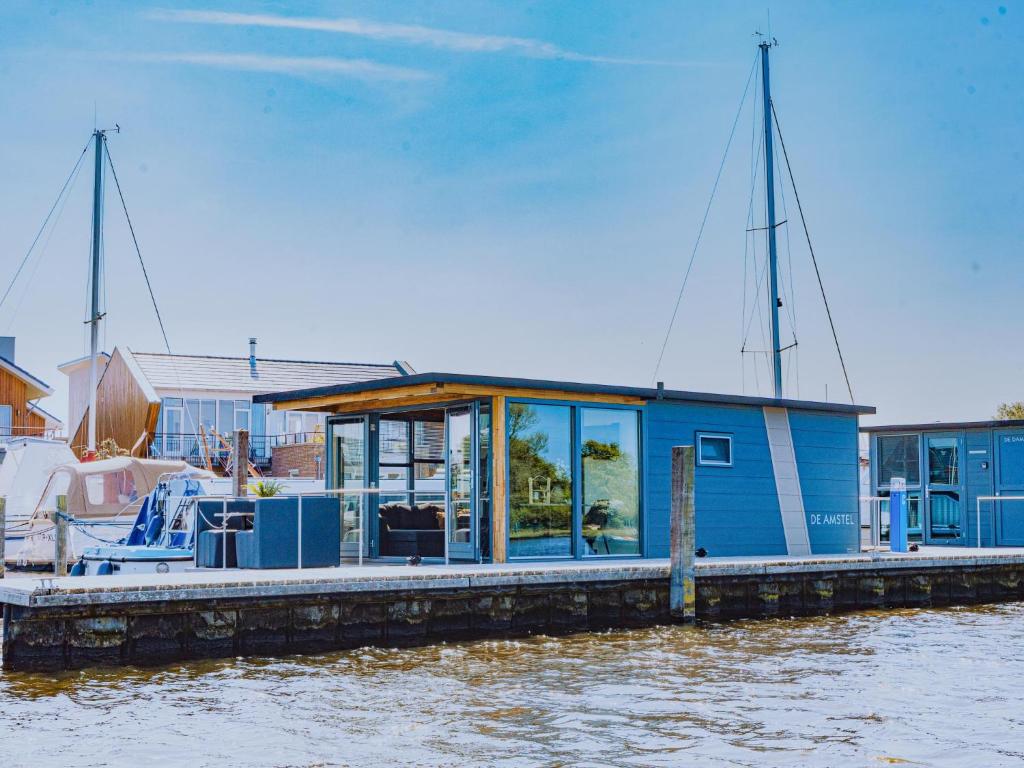 厄伊特海斯特Tiny houseboat Uitgeest I的水面上的一个蓝色房子