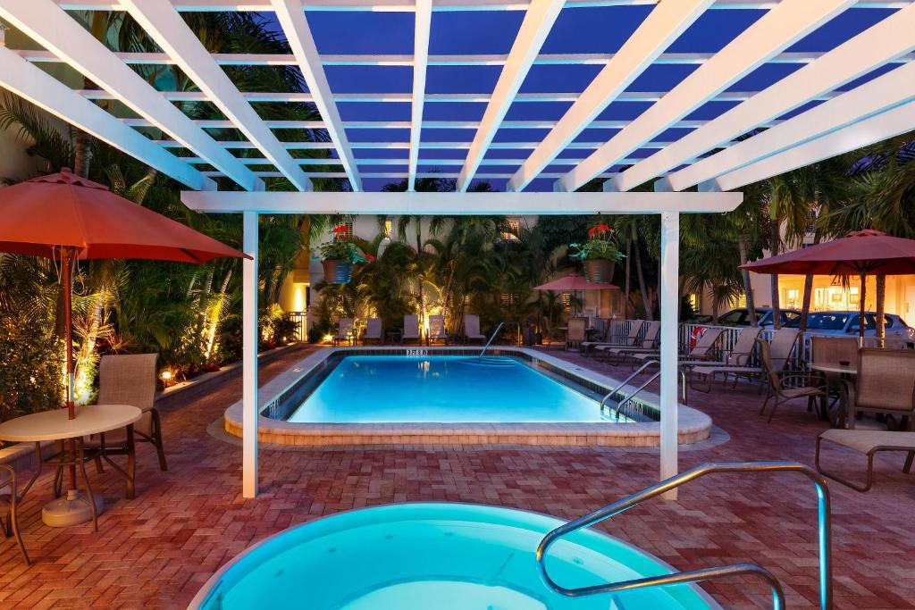 威尼斯Inn at the Beach-Venice FLORIDA的一个带蓝色天花板和桌椅的游泳池