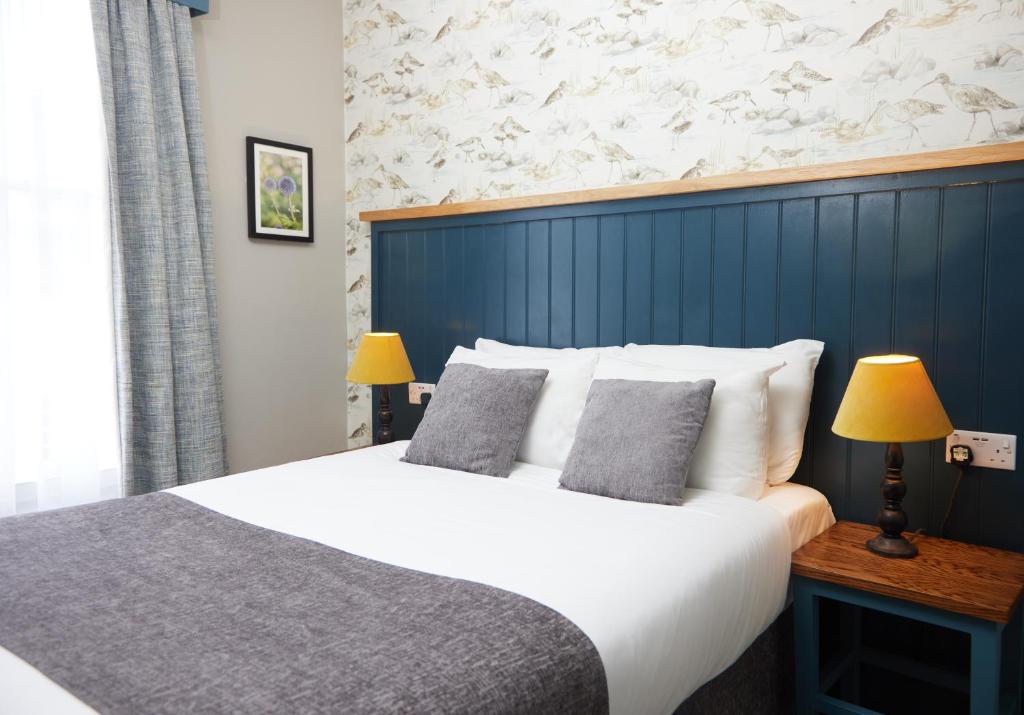 沃本The Bell Hotel Woburn By Greene King Inns的一间卧室设有一张蓝色墙壁的大床