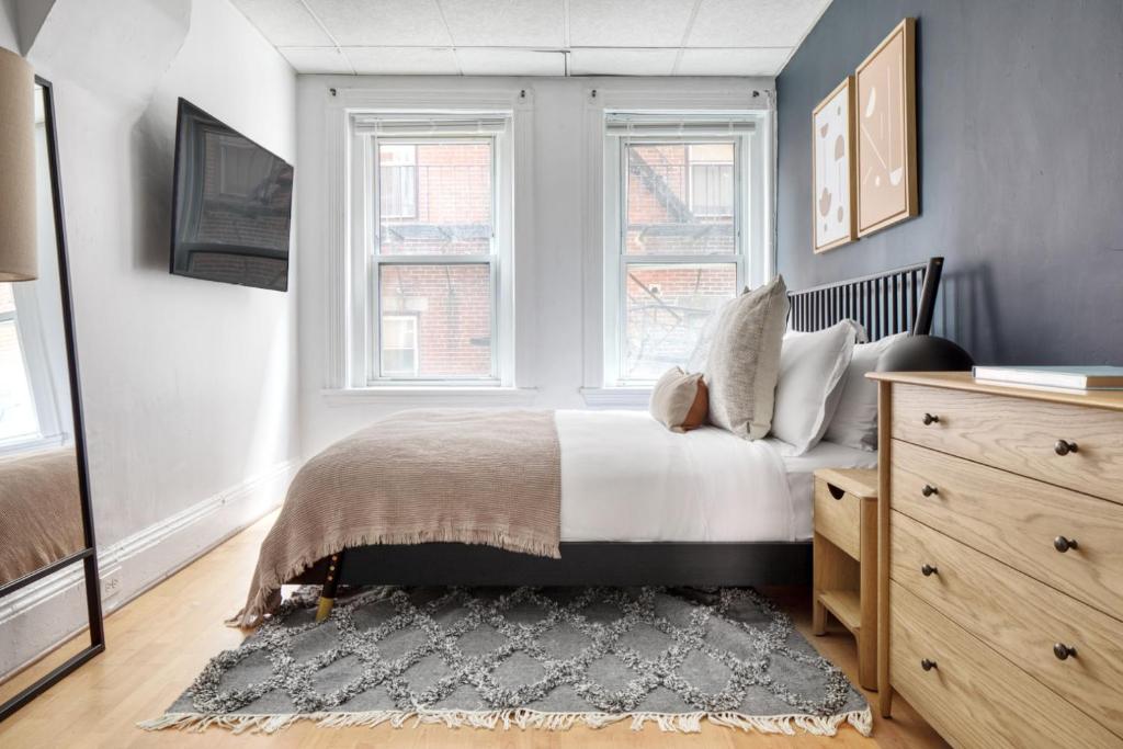 波士顿Cozy N End 1BR steps from Harborwalk BOS-446的一间卧室设有床、两个窗户和地毯。