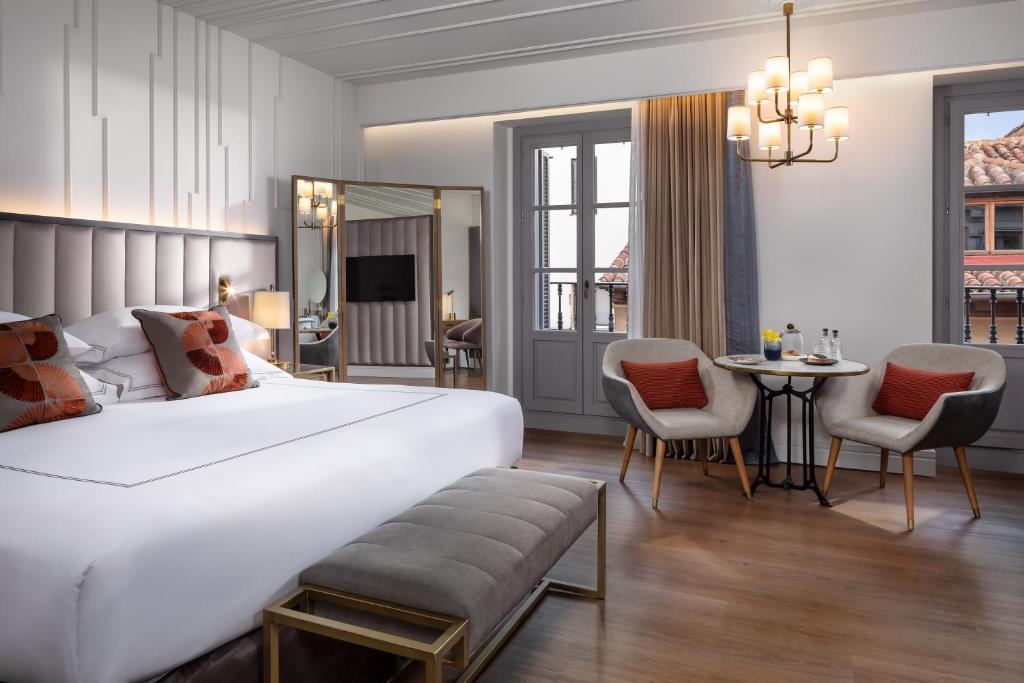 马德里Gran Hotel Inglés - The Leading Hotels of the World的一间卧室配有一张大床和一张桌子及椅子