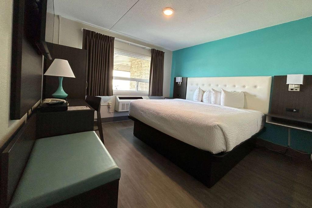 桑德贝Howard Johnson by Wyndham Thunder Bay的一间卧室设有一张大床和蓝色的墙壁