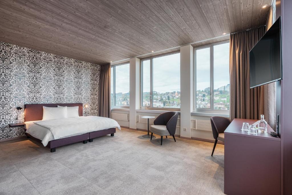 Menzikenb-smart hotel Menziken的一间卧室配有一张床、一张书桌和一些窗户。