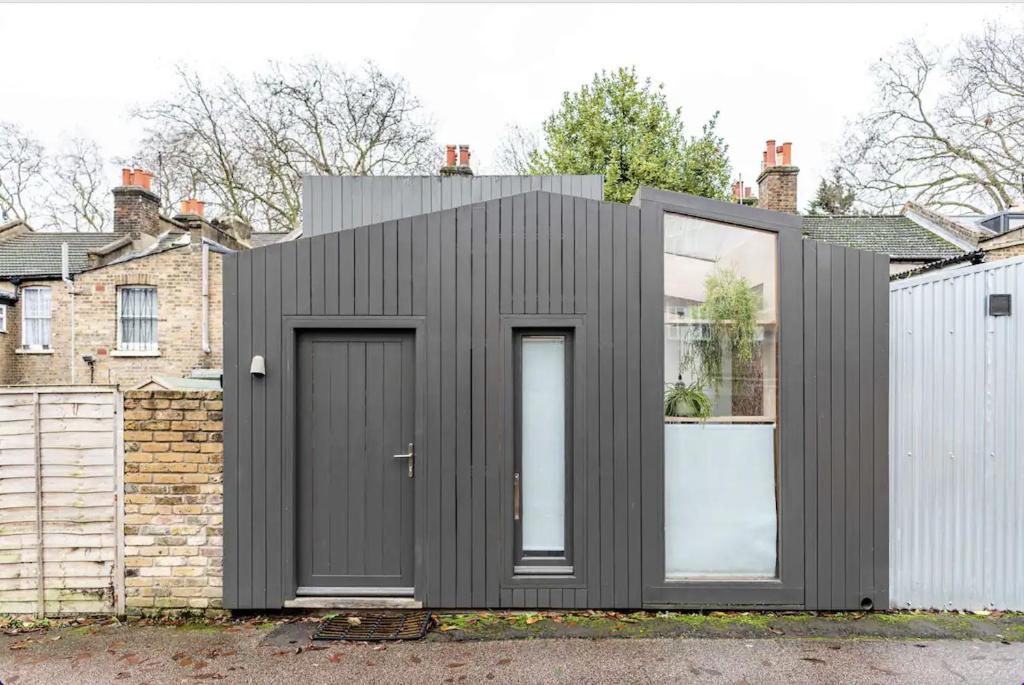 伦敦Entire Home on Victoria Park的一座带两扇门和栅栏的黑色房子