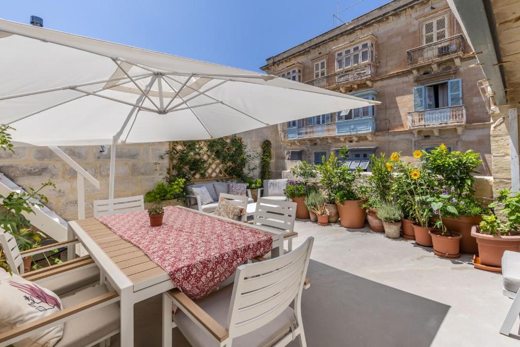 瓦莱塔Stunning Valletta Palazzino的天井配有桌子、雨伞和盆栽植物
