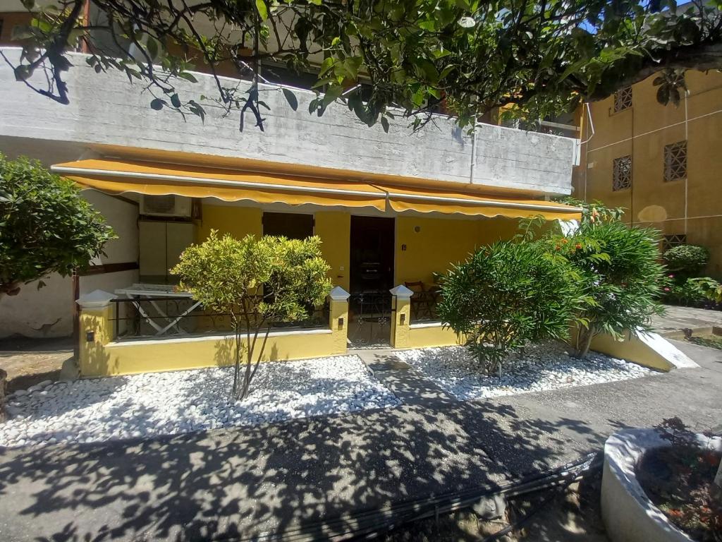AnálipsisAngela's Cute Apartment (A/C, WiFi, Little Garden)的前面有一张桌子和椅子的黄色建筑