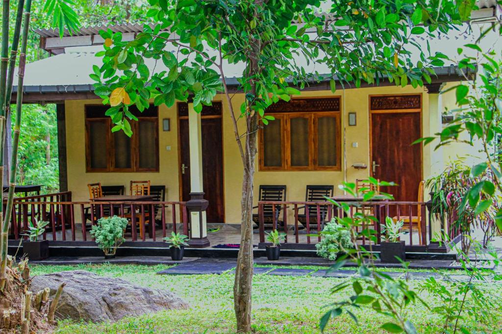 锡吉里亚Sigiri Nirwana Lodge的前面设有桌椅的黄色房子