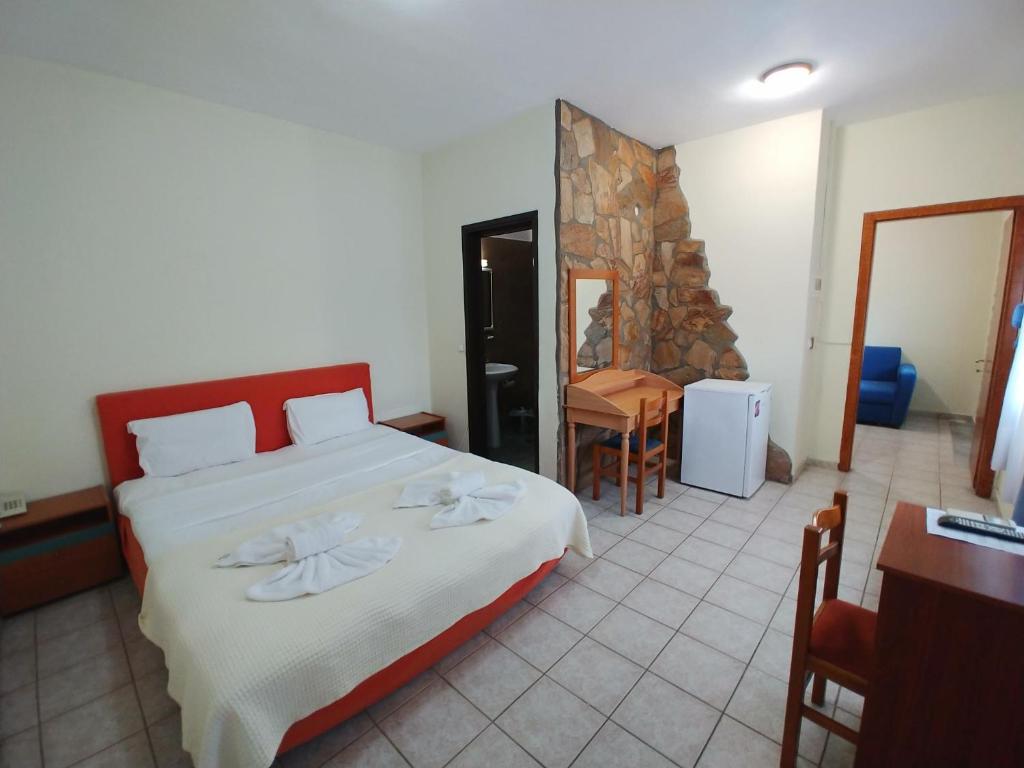 LágosPorto Vistonis的一间卧室配有一张大床和一张桌子及椅子