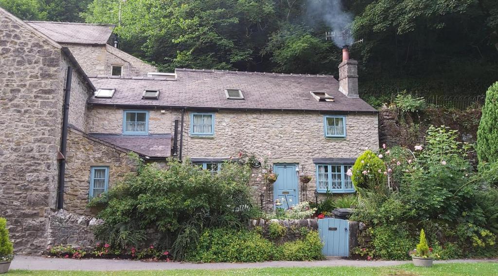 巴克斯顿Rose Cottage - Cosy cottage in Millers Dale的一座古老的石头房子,上面有烟 ⁇ 