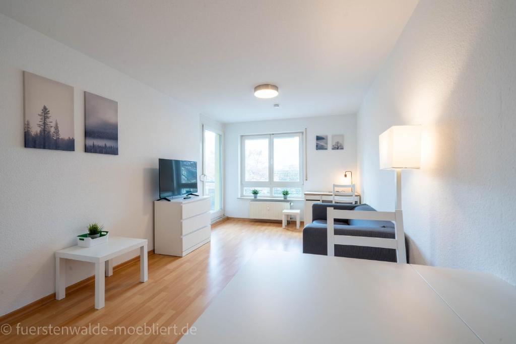 菲尔斯滕瓦尔德2 Zimmer mit Balkon, Wohnzimmer mit Arbeitsplatz, zentral, top!的带沙发和电视的白色客厅