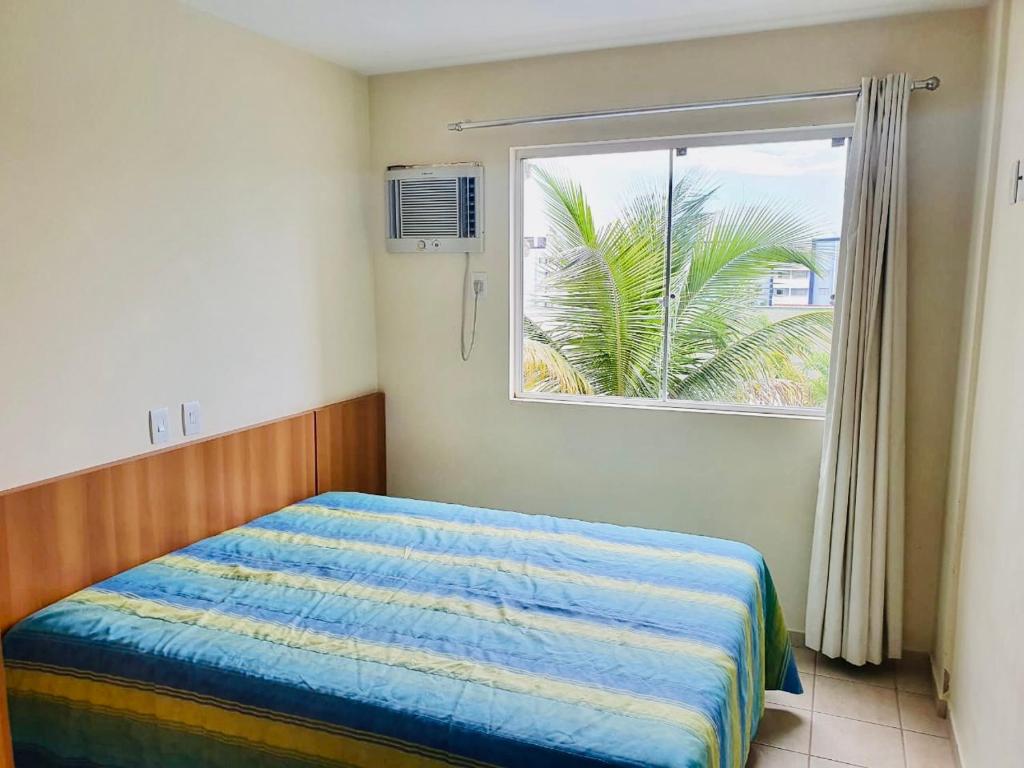 热河市Flat Pertinho do Hot Park (200m)! Aconchegante!的一间卧室设有一张床,窗户拥有棕榈树