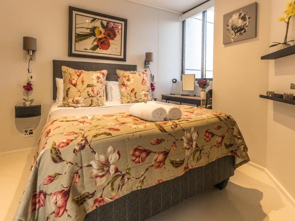 开普敦Flamingo Sea Point Sea View Luxury Best Position 1 Bedroom Apartment Queen Size Bed & Inverter For TV的一间卧室配有一张带花卉床罩的床