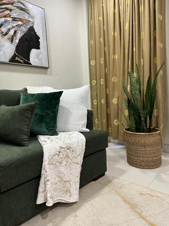 卢萨卡Kaya Apartments的客厅配有绿色沙发和植物