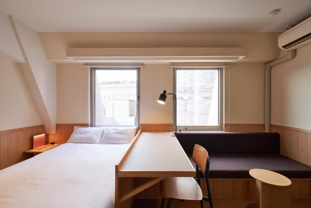 东京ホテルレジデンス大橋会館 by Re-rent Residence的一间卧室配有一张床、一张长凳和两个窗户。