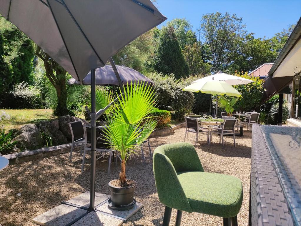 里摩日Hotel Be Guest Limoges Sud - Complexe BG的庭院配有桌椅和遮阳伞。