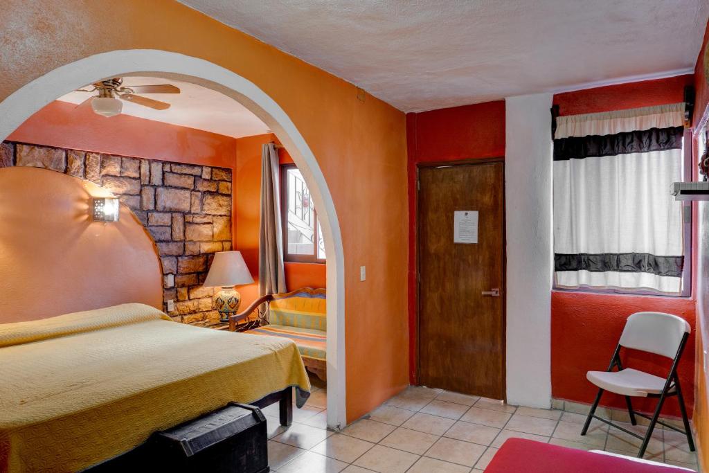 瓜纳华托Hotel Spa Casa del Sol的一间卧室拥有橙色的墙壁,设有一张床和一扇门