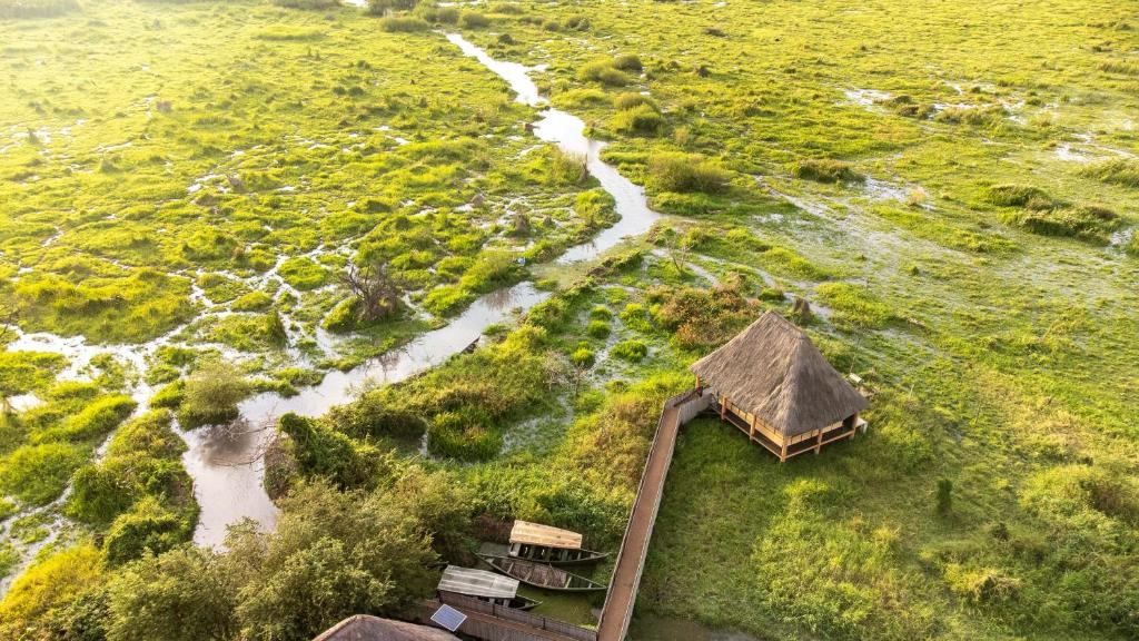 ItongaLittle Okavango Camp Serengeti, A Tent with a View Safaris的享有河流和小屋的空中景致