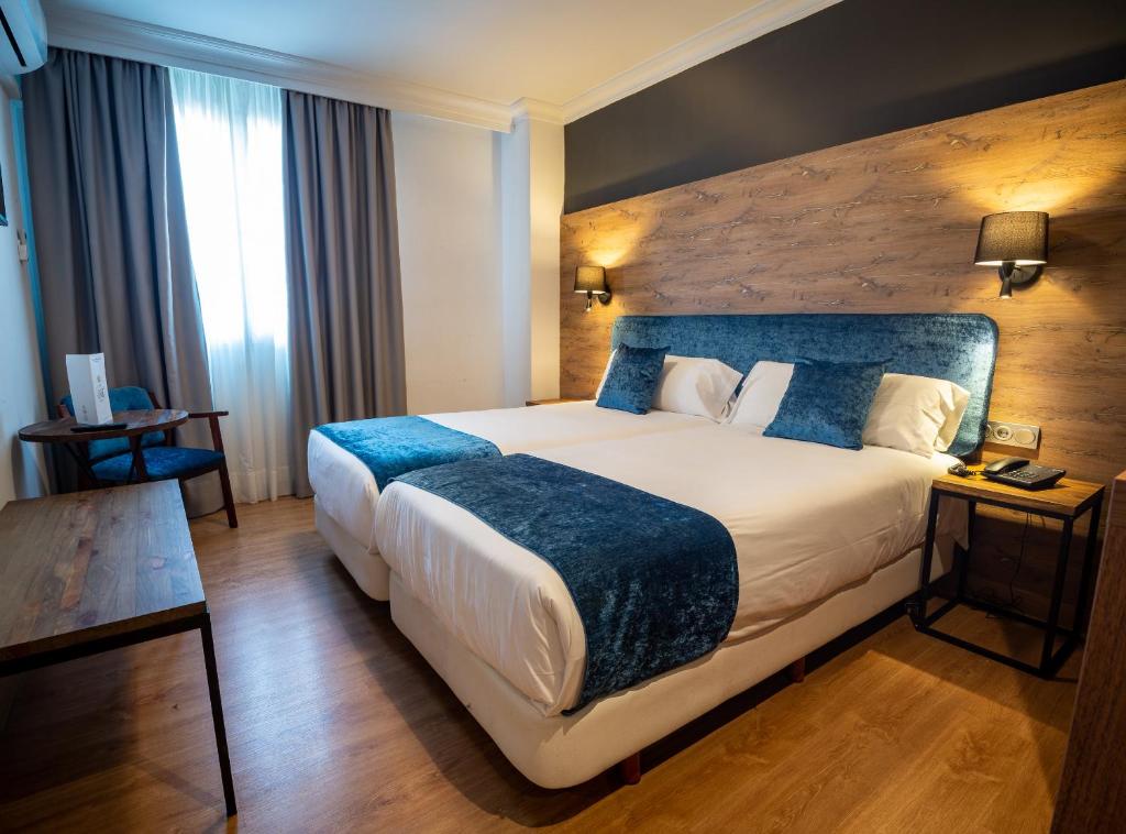 韦尔瓦Hotel Familia Conde的酒店客房配有一张带蓝色毯子的大床