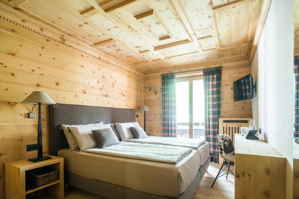 博尔米奥拉杰西安奈拉博尔米奥酒店的一间带一张大床的卧室,位于带木墙的房间