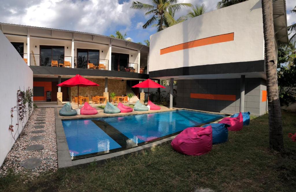 吉利特拉旺安Soda Resort Gili Trawangan的一座游泳池旁,游泳池旁摆放着五颜六色的椅子和遮阳伞