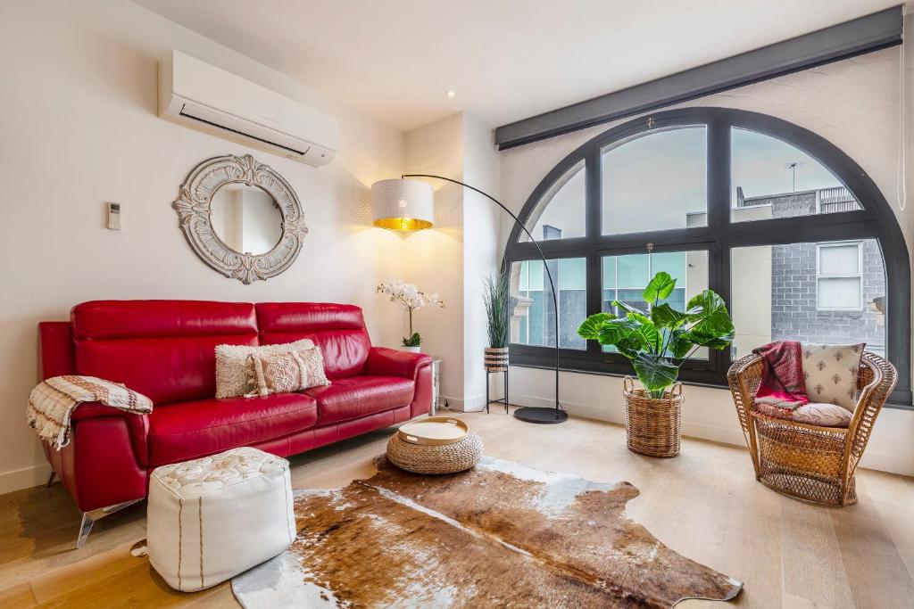 墨尔本Charming 1-Bedroom Heritage Apartment的客厅设有红色的沙发和大窗户
