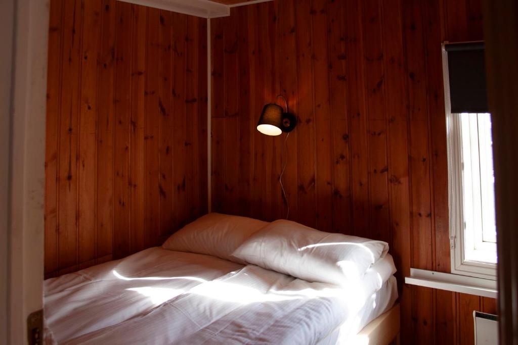 雷讷Authentic central located cabin close to Reinebringen Lofoten的木墙客房的一张床位