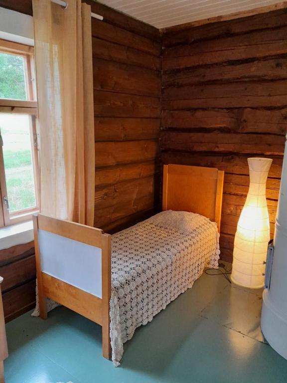 LohjaCozy cottage by the lake的卧室配有一张床铺,位于带木墙的房间内