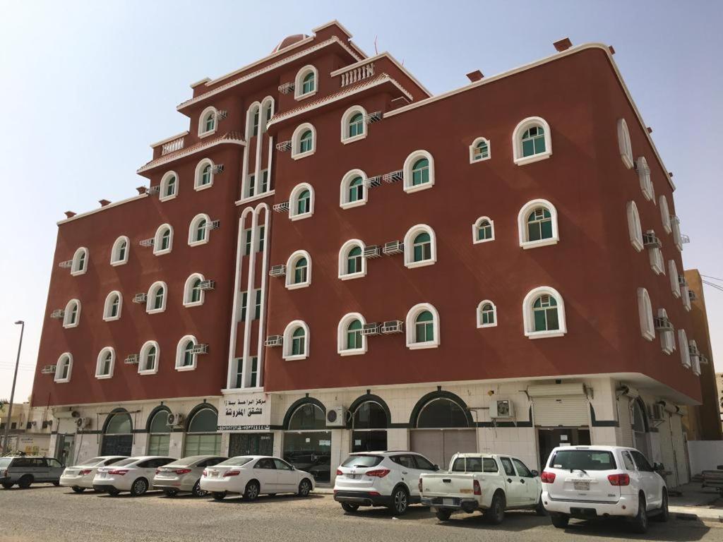 沙鲁拉الراحة بلازا للشقق المفروشة的一座大型红色建筑,前面有汽车停放