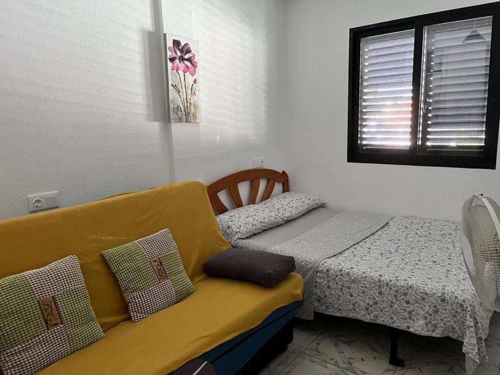 卡布罗伊格Apartment with Outdoor Pool and Air Conditioning in Cabo Roig的一间卧室配有一张床和一张黄色的沙发
