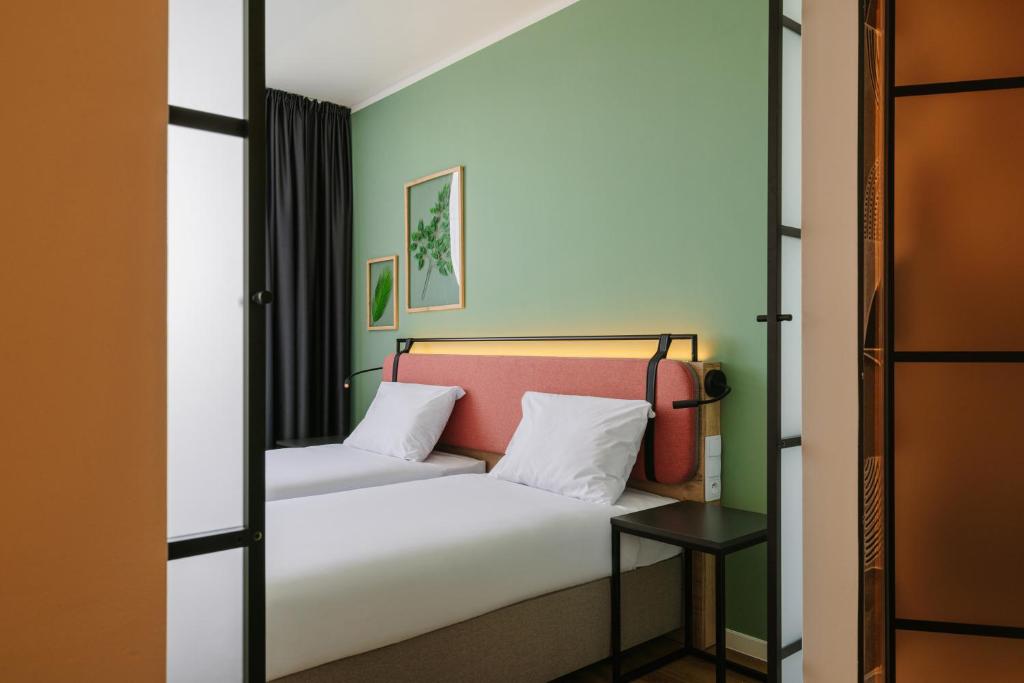 克拉科夫Campanile Krakow South的一间卧室配有一张带白色床单和绿色墙壁的床。