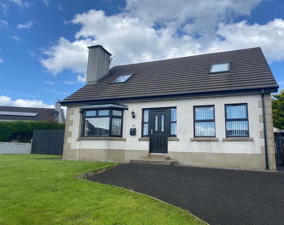 巴利卡斯尔Holiday Home in Ballycastle - Fáinne na Cairde的一间白色的房子,有黑色的门和一个院子
