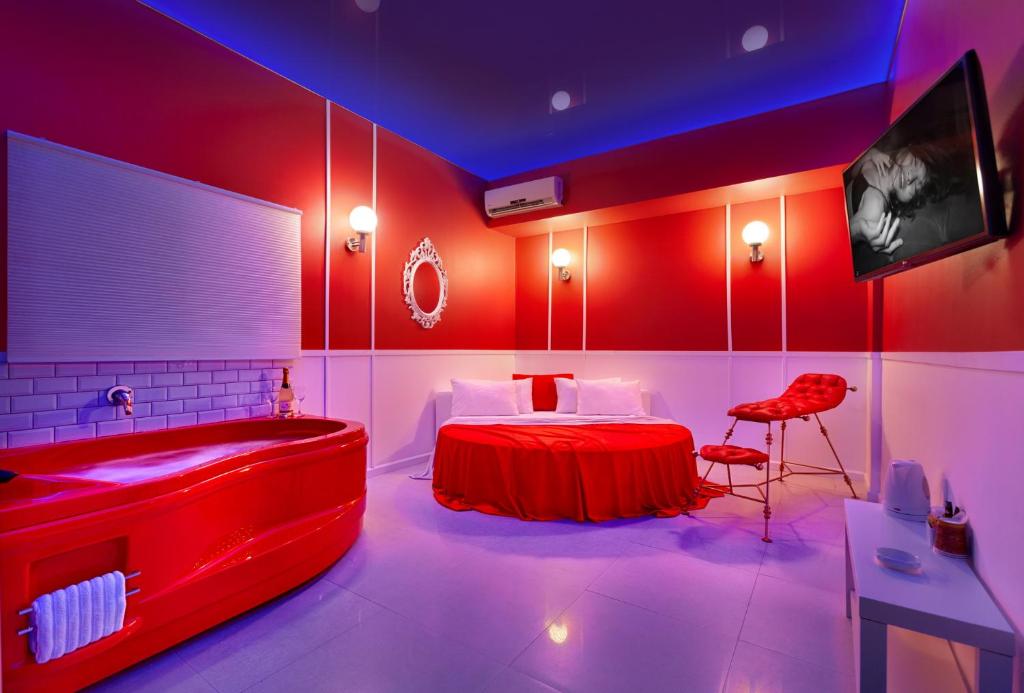Tel BinyaminMetro Elegance Suites的一间设有床铺和浴缸的房间和一间红色的房间
